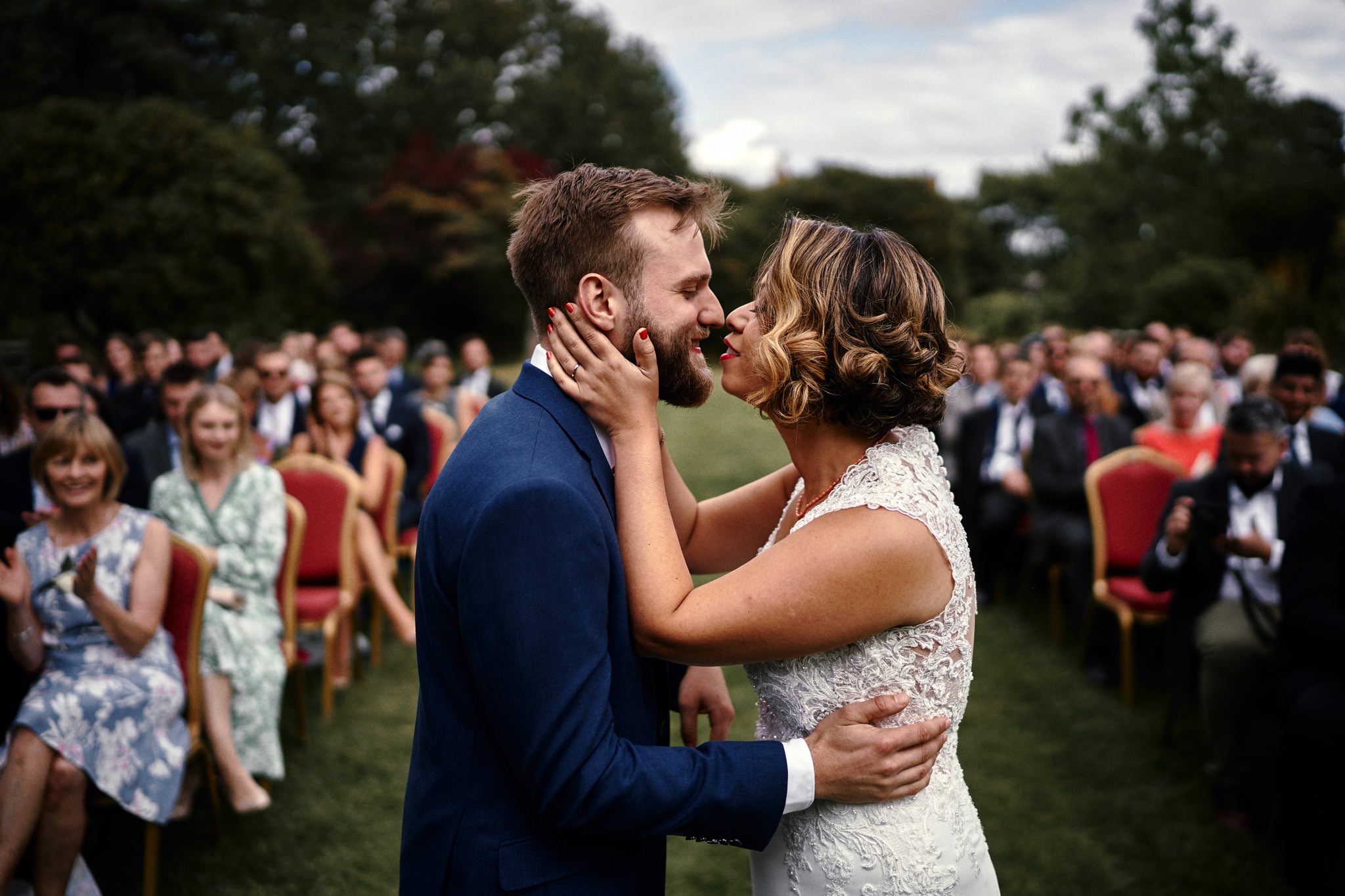 Bride and groom's first kiss during their wedding ceremony in the beautiful gardens at Walcott Hall Hotel, Shropshire.