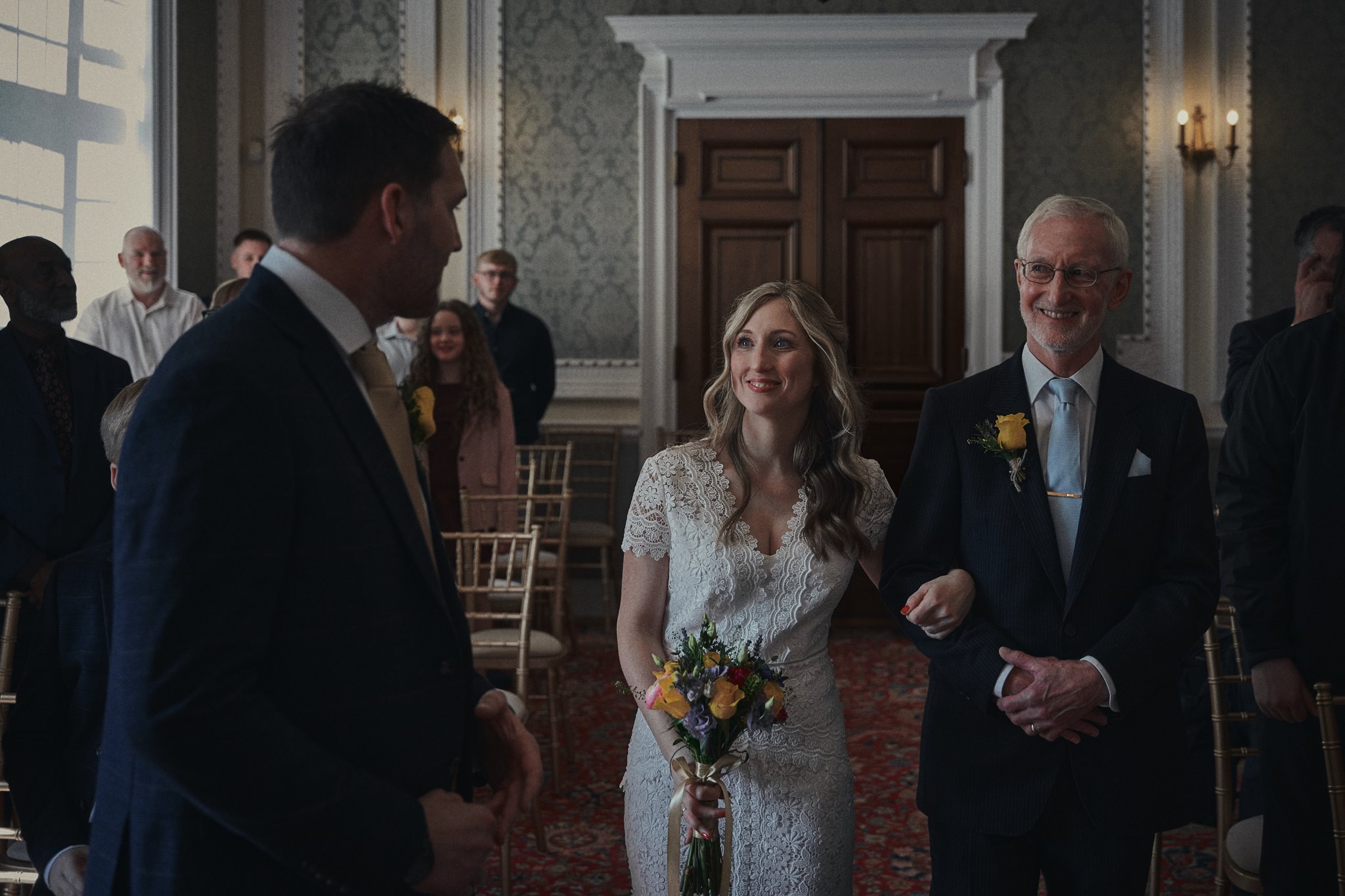 Bride arriving at Crewe Registry Office with her father, smiling at the groom during an intimate wedding ceremony in Cheshire.